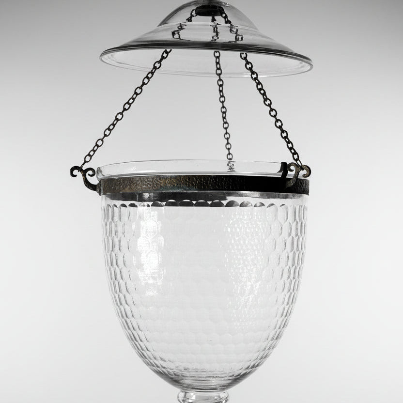 A vintage-style clear glass hanging lantern with a textured, dimpled surface, a dark metal rim, and hanging chains, shown against a white background.