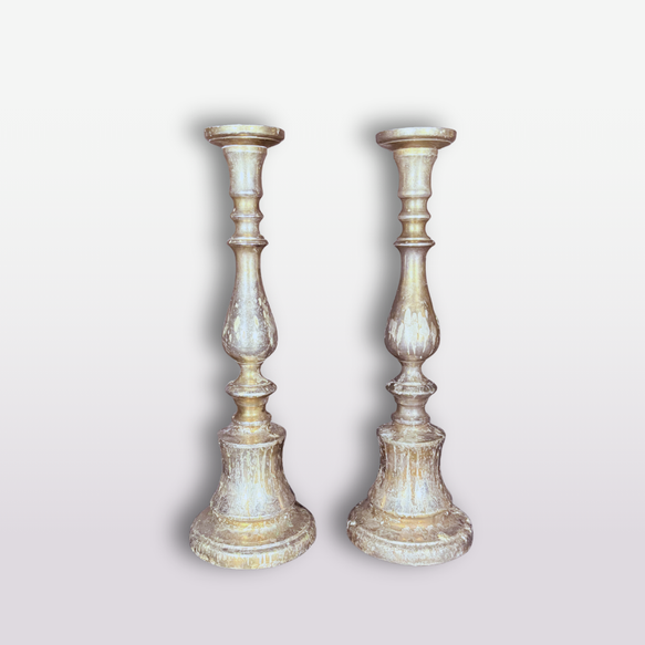 A pair of distressed silver and gold candlesticks standing side by side against a light gray gradient background.