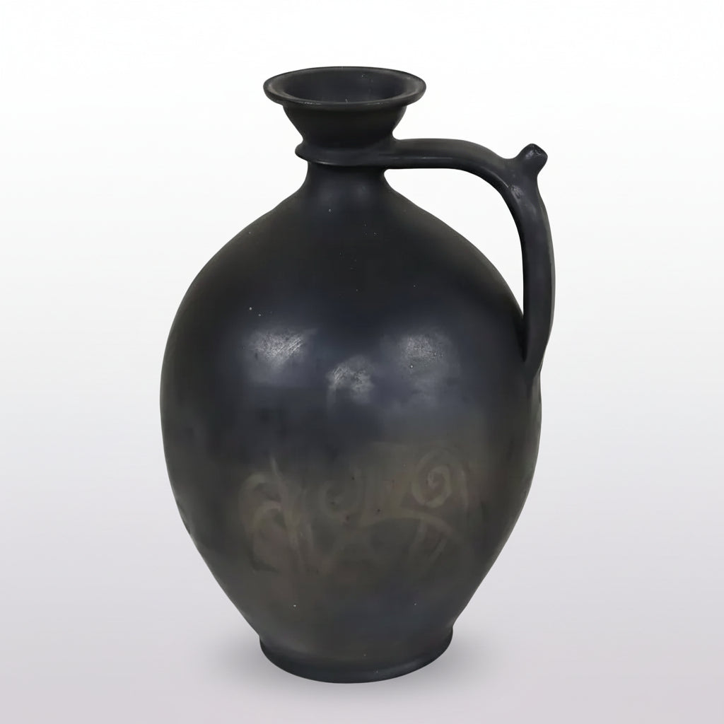 A striking antique French gargoulette in dark charcoal-black terracotta, distinguished by its generous ovoid body and elegantly curved handle terminating beside the neck.