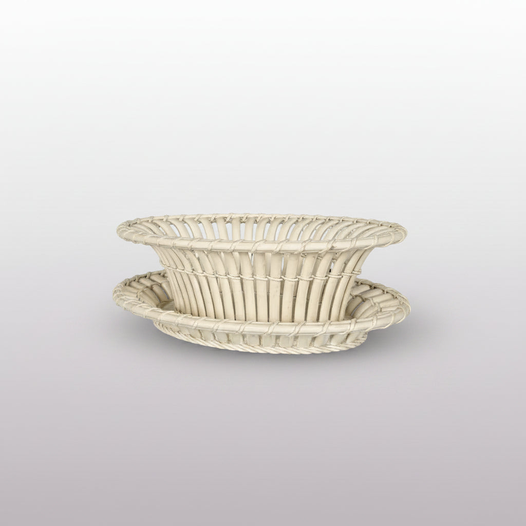 An off-white woven rattan basket with a matching oval tray, set against a dark gray background.