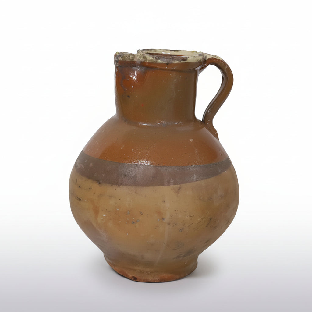 A tall French glazed stoneware pitcher in warm amber tones, with a single handle and pinched spout.