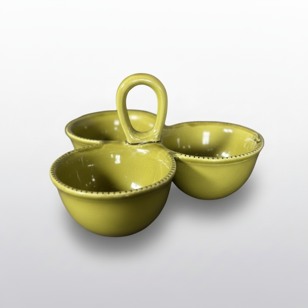 Three small olive green ceramic cups with a central loop handle, arranged on a dark tabletop against a gray wall.
