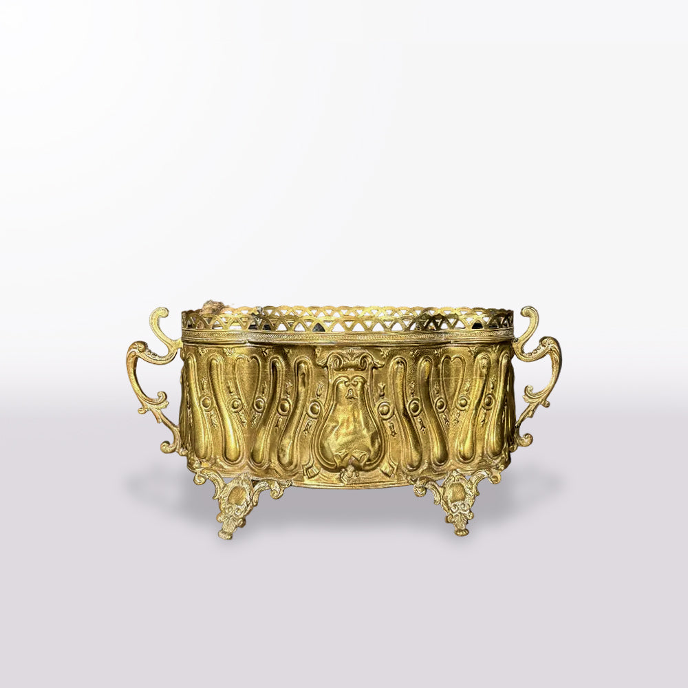 An ornate gold-toned metal candelabra with decorative handles, a pierced top rim, and sculpted feet, shown on a clean light gray gradient background.