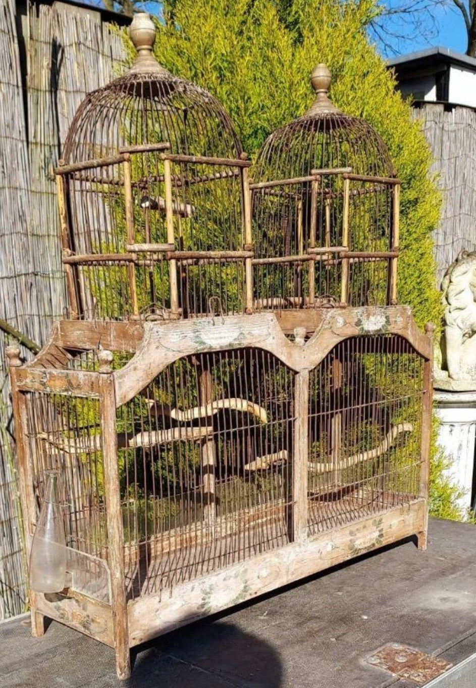 Large wooden birdcage with intricate design in an outdoor setting