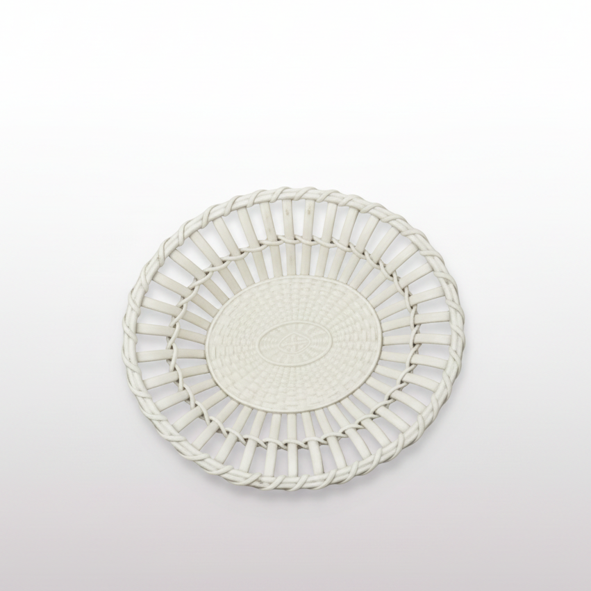 A round white plastic basket or shallow tray with a slotted, woven-like edge and a textured center, photographed against a dark gray background.