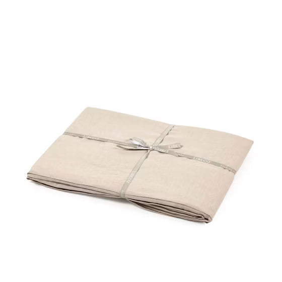 A folded beige linen sheet or blanket wrapped with a silver-gray ribbon and bow, set against a plain white background.