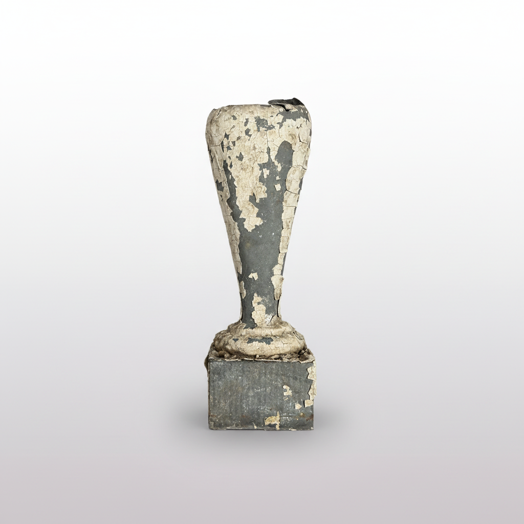 A weathered, vintage metal stamp handle with a conical shaft and square base, showing significant peeling white paint over a dark gray metal surface, set against a dark background.